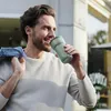 A man is drinking from a travel mug outdoors. Voir les images du produit
