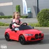 A young child is happily driving a red toy car outdoors. Voir les images du produit