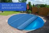 A round pool cover is shown on a paved patio next to a lawn and a wooden fence. Náhled obrázku produktu