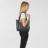 A woman is shown from the side, wearing a white t-shirt and black jeans, holding a tote bag over her shoulder. Voir les images du produit