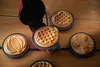 A red mini waffle maker with various shaped waffle plates on a wooden table. Produktbild-Vorschau