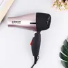 A rose gold and black hairdryer is placed on a white surface, with decorative flowers and leaves in the background. Produktbild-Vorschau