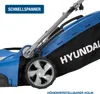 Close-up view of a blue electric lawnmower with a black grass catcher bag. Produktbild-Vorschau