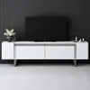 A modern white TV stand with a black television on top, set against a dark gray paneled wall. Voir les images du produit