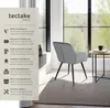 A chair is placed in a room with a large window overlooking a forest. A side table with a mug and book is next to the chair. The image also features a panel with product features and benefits. Náhled obrázku produktu