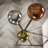 A floor lamp with three spherical, reflective shades in different metallic finishes, set against a herringbone wooden floor. Produktbild-Vorschau