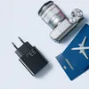 A travel-themed flat lay featuring a camera, passport, airplane model, and a black power adapter. Anteprima dell’immagine prodotto