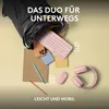 A pink keyboard and mouse are shown spilling out of a black backpack, along with a smartphone and notebook, on a light yellow background. Produktbild-Vorschau
