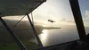Two small airplanes flying over a body of water near a coastline at sunset. Produktbild-Vorschau