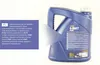 A blue plastic container of engine oil is shown against a white background. A purple informational label is partially overlaid on the container. Náhled obrázku produktu