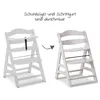 Two white wooden high chairs are shown side-by-side, with an arrow indicating a transition. The left chair has a safety bar and crotch strap, while the right chair does not, illustrating their removability. Podgląd zdjęcia produktu