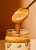 A spoon scoops peanut butter from a jar. Produktbild-Vorschau