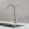 A kitchen faucet with a flexible gray hose is shown in a modern kitchen setting, with a double sink visible. Produktbild-Vorschau