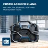 A rugged, portable radio with a digital display and controls, set against a backdrop of construction materials. Produktbild-Vorschau