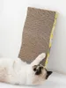 A cat is lying on its back and scratching a cardboard scratching board that is leaning against a white wall. Náhľad obrázku produktu
