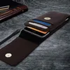 A brown leather phone pouch with a phone and cards inserted, shown on a textured gray surface. Náhled obrázku produktu