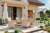 An outdoor patio set with a table and chairs, set in a garden. Náhled obrázku produktu