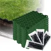 A stack of green hexagonal grid panels for ground reinforcement, with some black stakes in clear plastic packaging in the foreground. A section of grass with a hexagonal grid embedded in it is visible in the background. Produktbild-Vorschau
