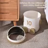 A cute astronaut-themed trash can with a detached lid sits on a carpeted floor next to a wooden dresser. Produktbild-Vorschau
