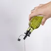 A hand is pouring oil from a green glass bottle with a black dispenser. Produktbild-Vorschau