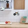 A kitchen counter with a tiled backsplash, featuring a decorative bicycle hook, a cutting board, and fruit. Produktbild-Vorschau