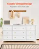 A white dresser with nine drawers is shown in a room, with decorative items on top and a rug on the floor. Voir les images du produit