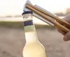 A hand is using a bottle opener tool to open a bottle of drink outdoors. Produktbild-Vorschau