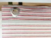 A close-up view of a striped roller blind with a metallic triangular loop attached. Produktbild-Vorschau