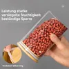 A hand holding a glass jar filled with peanuts, showcasing its sealing feature. Produktbild-Vorschau