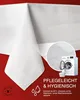 A white tablecloth is draped over a surface, with a circular inset showing a washing machine and laundry basket. Text and icons related to care and hygiene are present. Produktbild-Vorschau