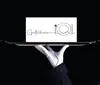 A hand in a white glove holds a silver tray with a card that says "Gutschein" and has a drawing of a plate, fork, and knife. Produktbild-Vorschau