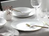 A table setting with white plates and gold accents, a vase with dried flowers, and glassware. Náhľad obrázku produktu