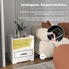 A white bedside table with a drawer and an open shelf with yellow LED lighting is shown next to a sofa. Text overlays describe the product's features. Produktbild-Vorschau