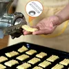 A person is using a cookie press attachment for a meat grinder to make cookies, with a tray of finished cookies in the foreground. Produktbild-Vorschau