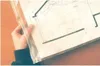 A hand holding a transparent plastic sleeve containing architectural plans. Produktbild-Vorschau