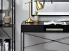 A close-up view of a black desk with a gold lamp, a small plant, and an open book. Voir les images du produit
