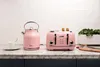 A pink kettle and toaster are displayed on a marble countertop in front of a white brick wall. Produktbild-Vorschau
