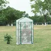 A small greenhouse with shelves filled with plants, placed on a grassy lawn with trees in the background. Voir les images du produit