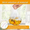 A hand holding a clear plastic bag filled with yellow tomatoes, with a kitchen window in the background. Produktbild-Vorschau