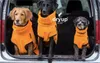Three dogs of different breeds and sizes are sitting in the back of a car, all wearing orange coats. Produktbild-Vorschau