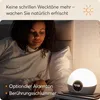 A woman is waking up in bed, with a light alarm clock on her nightstand. Produktbild-Vorschau