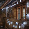 String lights on a wooden porch railing at dusk. Produktbild-Vorschau