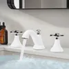 A white faucet with chrome handles is shown in a bathroom sink, with water running. Produktbild-Vorschau
