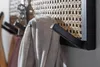 Close-up of a wall-mounted coat rack with hooks and a woven panel, holding a gray garment. Produktbild-Vorschau