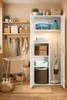 A well-organized laundry room or utility space with a white cabinet filled with cleaning supplies and towels, shelves with storage baskets and bottles, and a drying rack. Anteprima dell’immagine prodotto