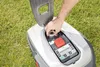 A person's hand is adjusting a dial on a robotic lawnmower. Produktbild-Vorschau