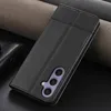 A black leather phone case with a wallet and stand feature is displayed on a dark surface with textured fabric in the background. Produktbild-Vorschau
