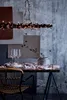 A table setting with wine glasses, plates, and decorative lights, set against a textured wall. Produktbild-Vorschau