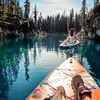 A person and a dog on a paddleboard in a lake surrounded by trees. Podgląd zdjęcia produktu