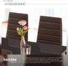 Two brown chairs in a dining room setting with flowers and a vase on a table. Náhled obrázku produktu